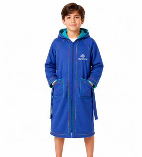 A young boy wearing a royal blue hooded bathrobe with teal lining and multicolor piping details, standing against a plain white background.